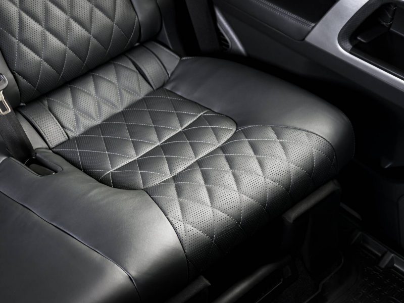 Back passenger seats in modern luxury car, frontal view, black perforated leather with stitching
